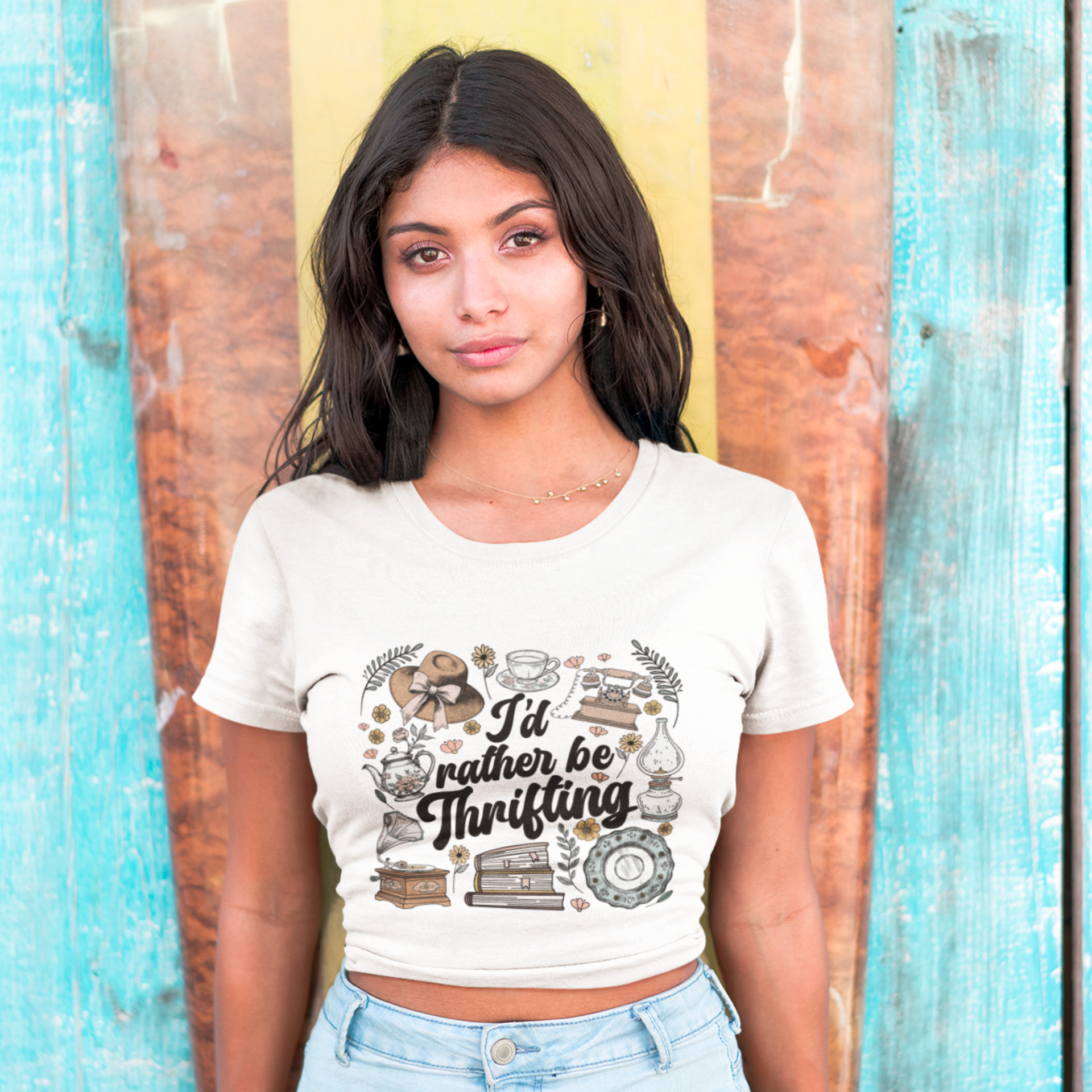 Woman wearing a white t-shirt with 'I'd rather be Thrifting' design against a colorful wooden background