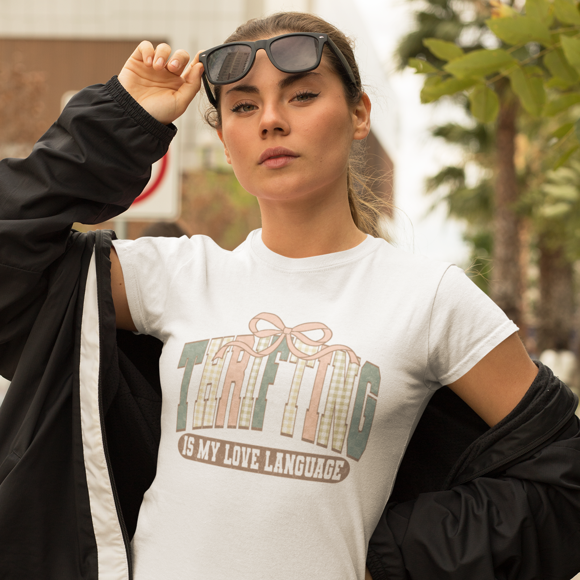 Woman wearing a white t-shirt with a graphic design and text, standing outdoors.