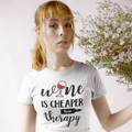Person wearing a white t-shirt with 'wine is cheaper than therapy' text, holding flowers.